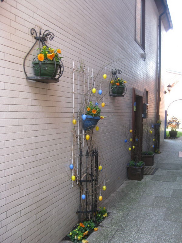 Easter Garden Decoration. Fasten the flower pot on iron railing and cover some branches, hang yellow and blue Easter eggs on all the branches. You will get this beautiful garden design Easter decoration. 