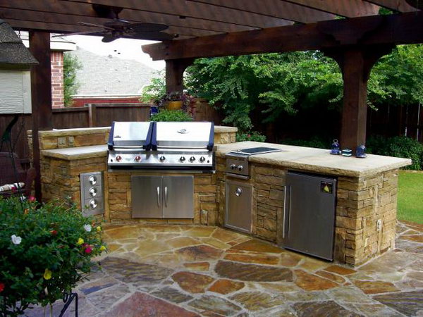 This stone outdoor kitchen features a refrigerator, grill, sink and storage, looking simple but fully functional. The wood roof and the stone structure are ideal and cool when cooking and dining during the summer night. 