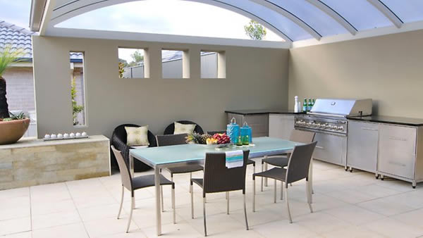 This is a typically modern outdoor kitchen with the glass roof and the grey, white and black elements. 