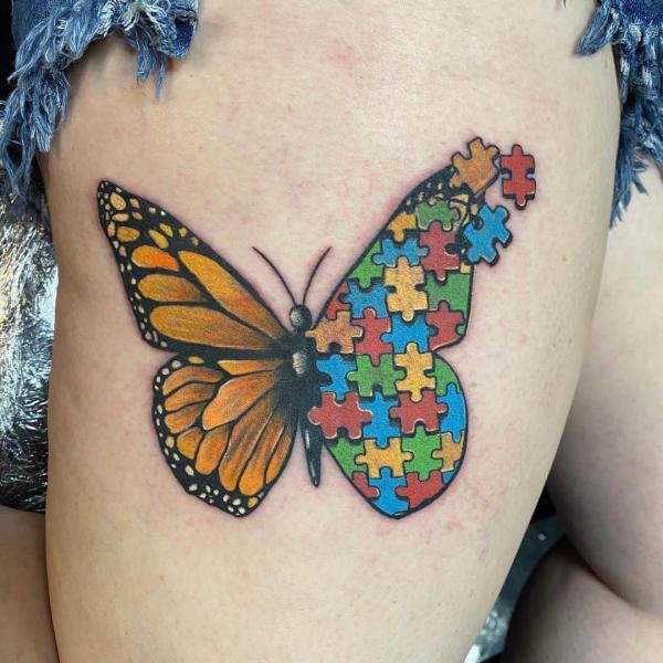 Half monarch butterfly half Autism puzzle tattoo on thigh