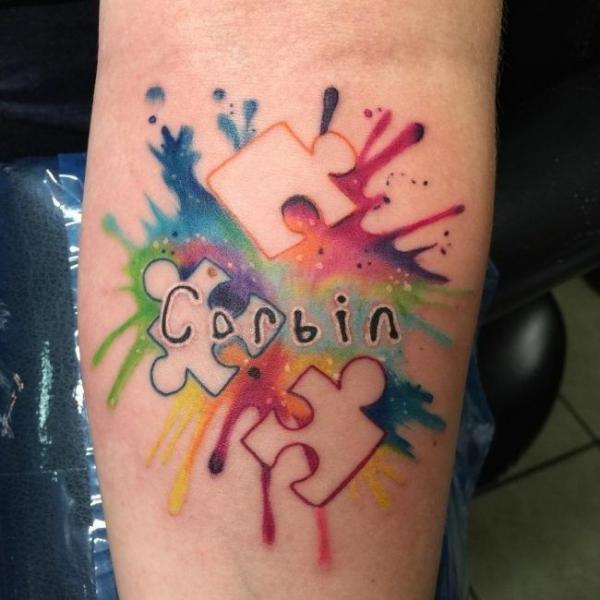 Negative space puzzle pieces watercolor tattoo with name