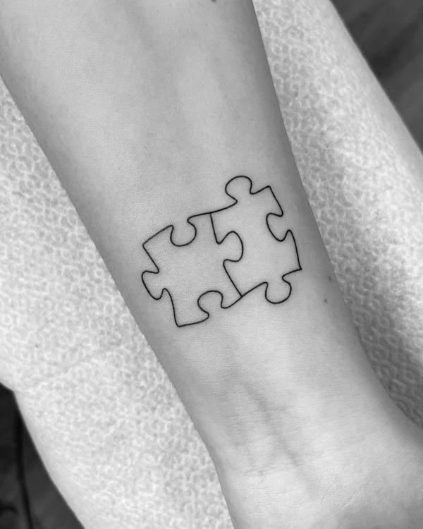 Two puzzle pieces line work tattoo