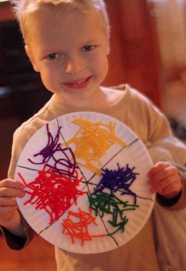 Lijm het garen aan de papieren plaat en maak een eenvoudig garenkleurenwiel voor kinderen. 