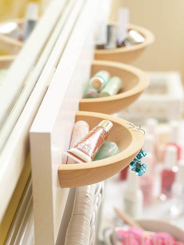 Wall pockets made by cutting wooden bowls in half and mounting them on a painted board in the bathrooom. 