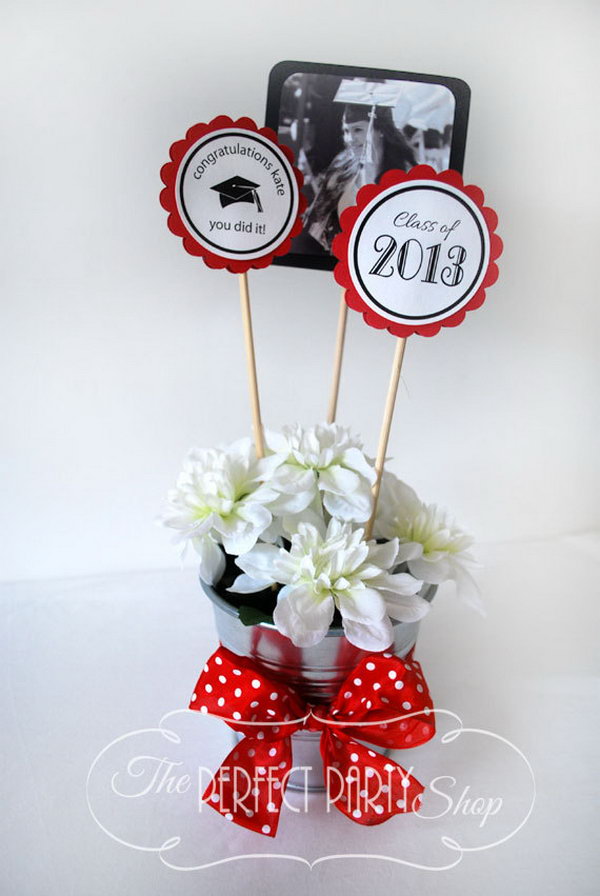 Graduation Centerpiece Stick. Decorate your graduation party with these centerpiece sticks to carry out your party theme. Use a galvanized bucket, Styrofoam, silk flowers as well as a pretty ribbon to finish off your pretty party table decor.