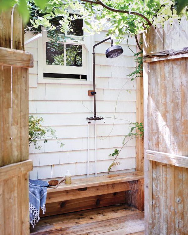 This outdoor shower features a classic design with a wall-mounted showerhead and a wooden floor for a natural look.